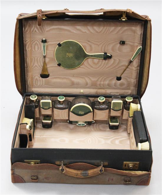 A 1920s silver, ivory and shagreen mounted travelling toilet set, in Asprey fitted leather case, monogrammed case 22.5in.